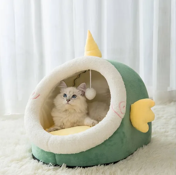 Fluffy white cat resting inside a green fish-shaped plush bed